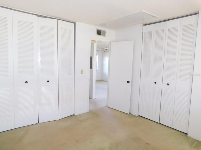 unfurnished bedroom featuring attic access, concrete floors, and visible vents