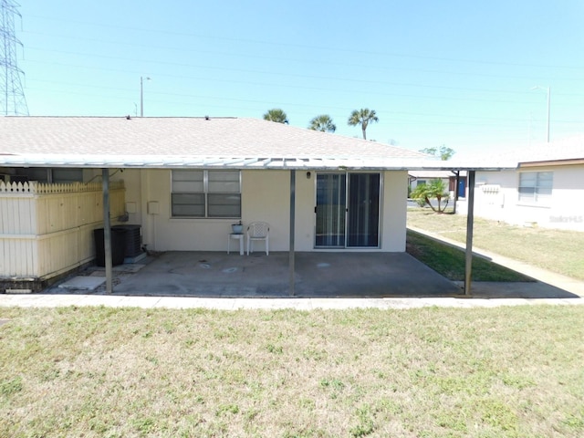 rear view of property with a shingled roof, central AC unit, a lawn, a patio area, and stucco siding