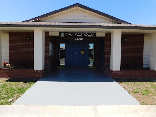 doorway to property with concrete driveway and brick siding