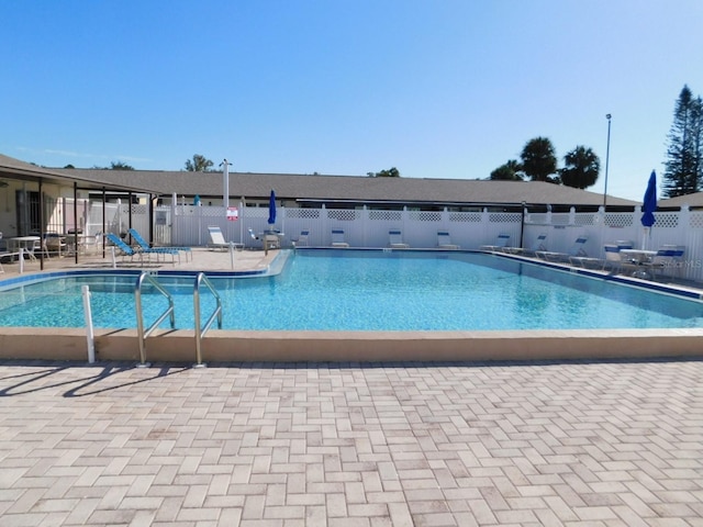 community pool with a patio area and fence