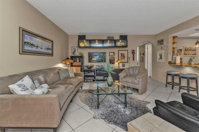 tiled living room with arched walkways and a sink