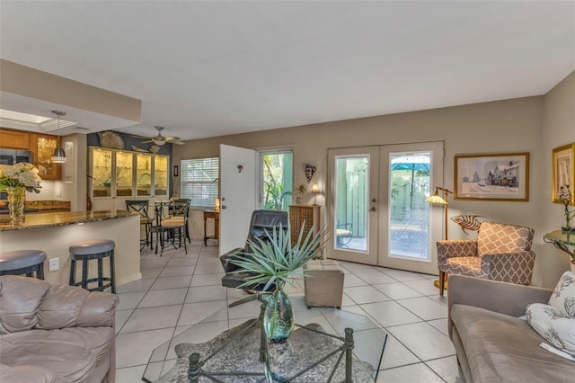 living area with light tile patterned floors, a ceiling fan, and french doors