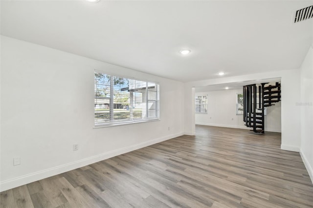 unfurnished living room with recessed lighting, visible vents, wood finished floors, baseboards, and stairs