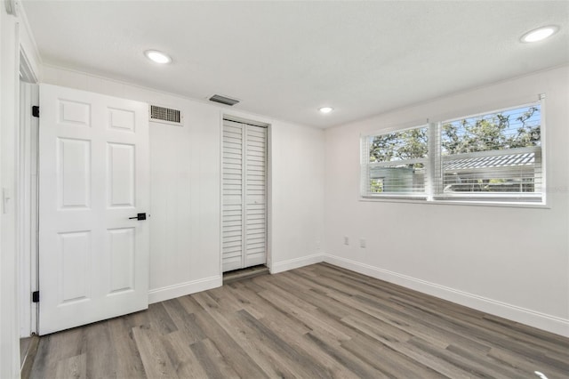 unfurnished bedroom with recessed lighting, a closet, visible vents, wood finished floors, and baseboards