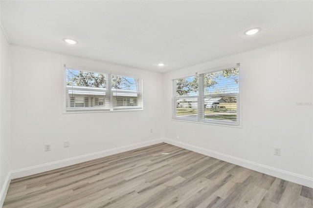 empty room with light wood-type flooring, baseboards, and recessed lighting