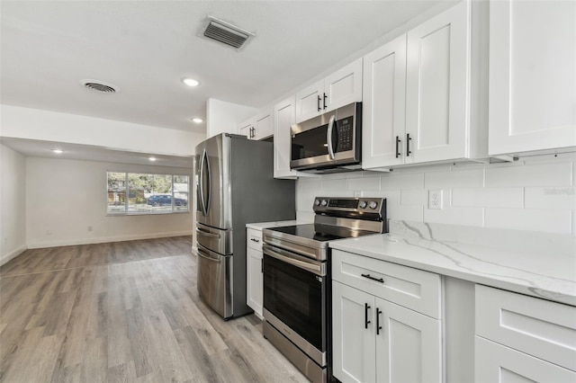 kitchen with stainless steel appliances, backsplash, visible vents, and white cabinets