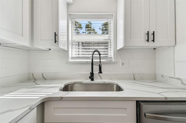 kitchen featuring light stone counters, white cabinetry, dishwasher, and decorative backsplash