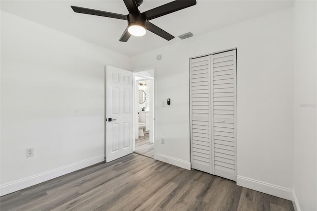 unfurnished bedroom featuring baseboards, a closet, visible vents, and wood finished floors