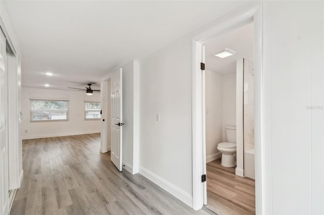 corridor with light wood-type flooring and baseboards