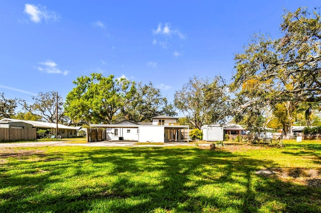 rear view of house featuring a lawn and fence