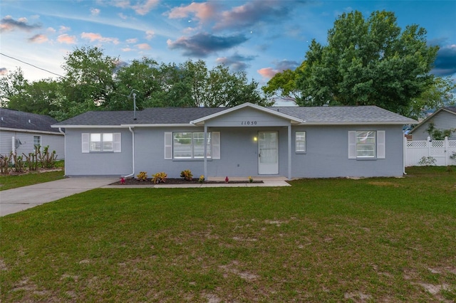 ranch-style house with a front yard, fence, and stucco siding