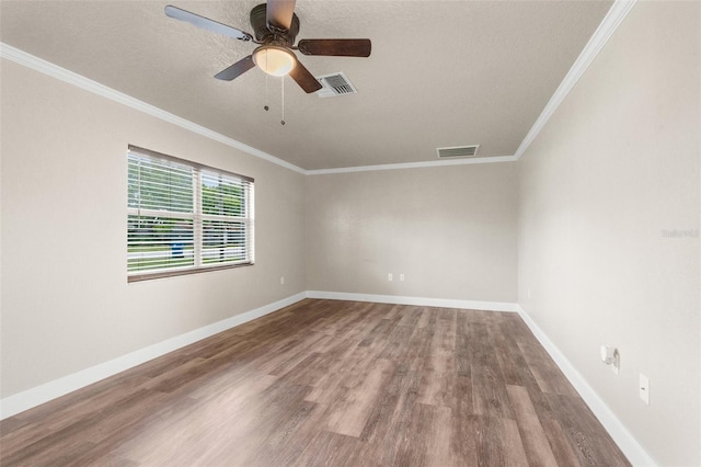 spare room featuring visible vents, ornamental molding, a ceiling fan, wood finished floors, and baseboards