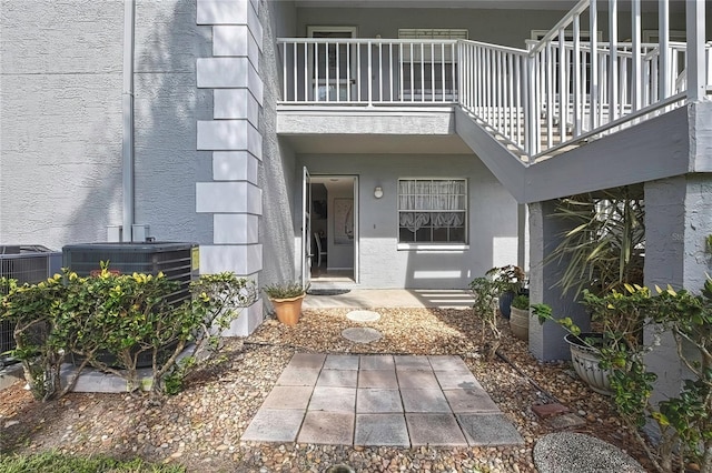 property entrance with cooling unit, a balcony, and stucco siding