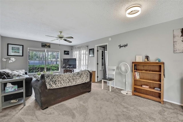 living room featuring a textured ceiling, carpet flooring, a ceiling fan, and baseboards