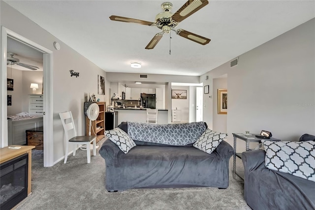 carpeted living room with visible vents and a ceiling fan