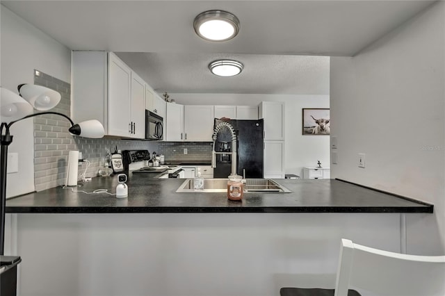 kitchen with a peninsula, white cabinetry, backsplash, black appliances, and dark countertops