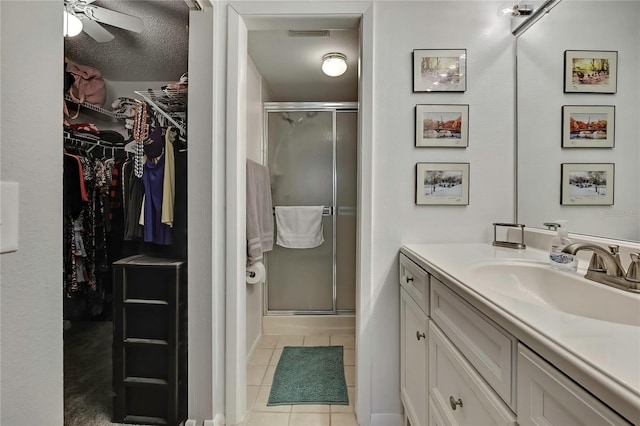 full bath featuring a spacious closet, a shower stall, vanity, and tile patterned floors