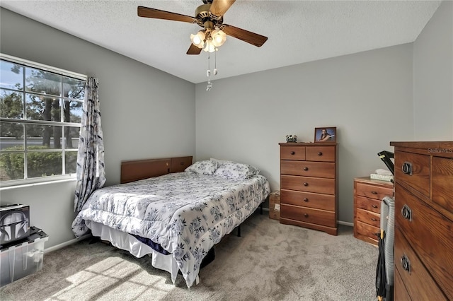 carpeted bedroom with ceiling fan, baseboards, and a textured ceiling