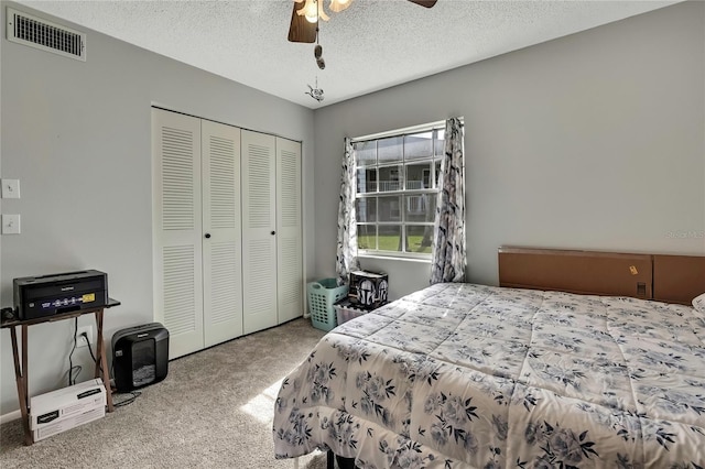 carpeted bedroom with a ceiling fan, a textured ceiling, visible vents, and a closet