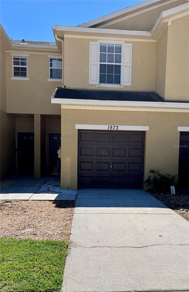 multi unit property with concrete driveway, an attached garage, and stucco siding