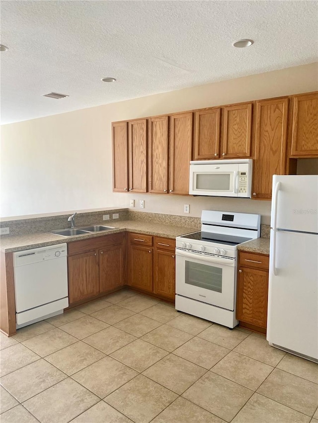 kitchen with brown cabinets, white appliances, visible vents, and a sink