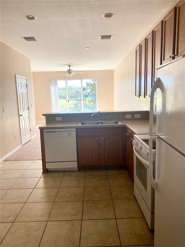 kitchen featuring white appliances, light tile patterned floors, visible vents, and a sink