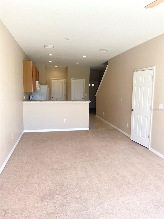 unfurnished living room with visible vents, light colored carpet, stairway, and baseboards