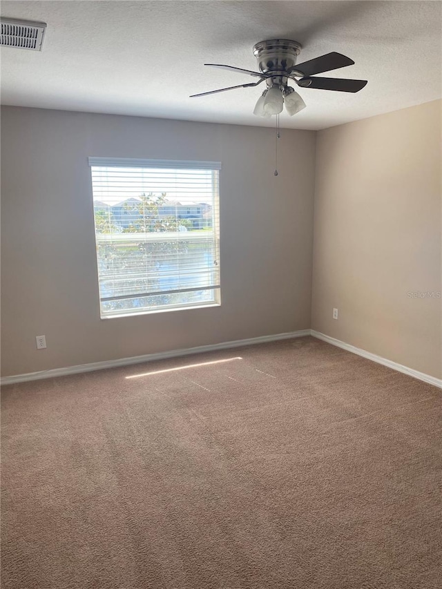 spare room with a textured ceiling, carpet, visible vents, and baseboards