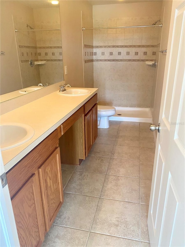 full bathroom with tiled shower, a sink, and double vanity