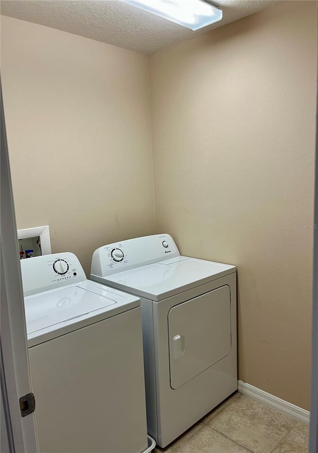 laundry room with a textured ceiling, laundry area, washer and clothes dryer, and baseboards