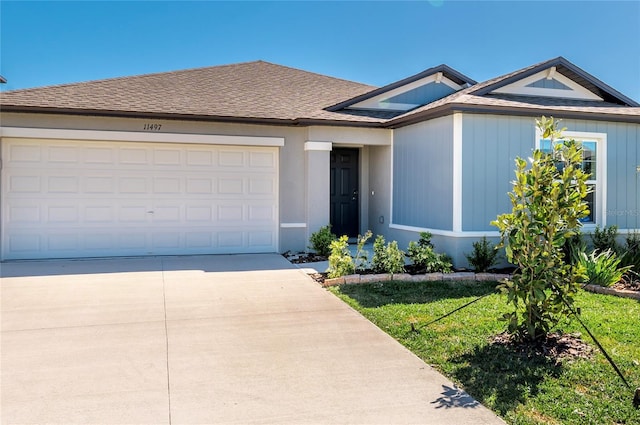 view of front facade featuring a garage, a shingled roof, and concrete driveway