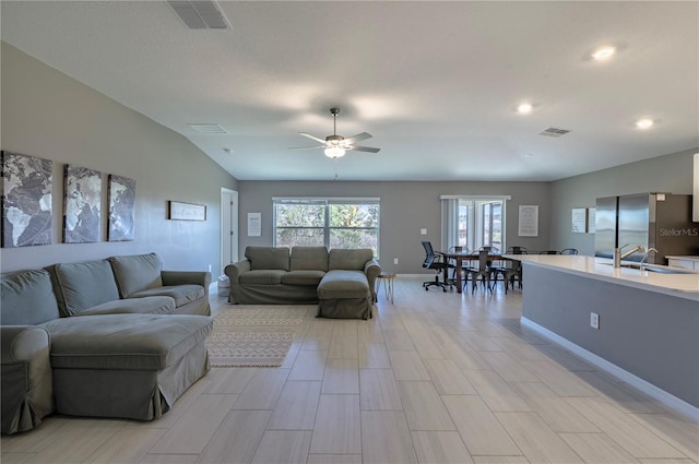 living area with lofted ceiling, visible vents, and baseboards