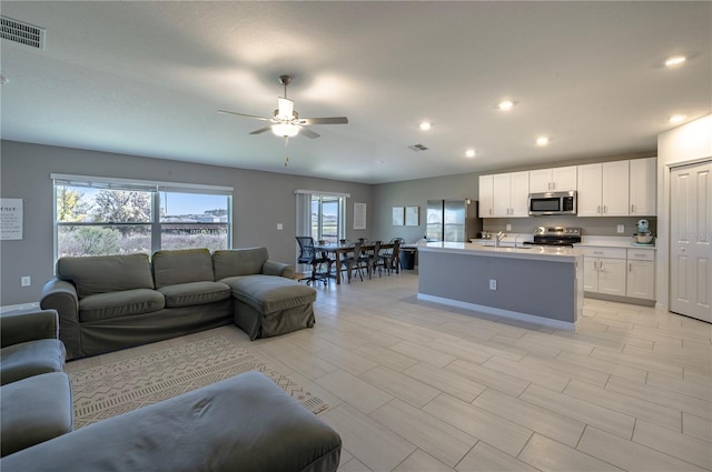 living room with a ceiling fan, visible vents, and recessed lighting