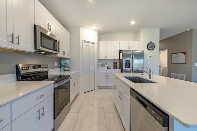 kitchen with appliances with stainless steel finishes, a kitchen island with sink, light countertops, and a sink