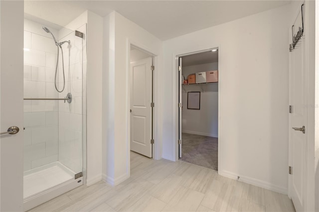 full bath featuring a shower stall, a walk in closet, and baseboards