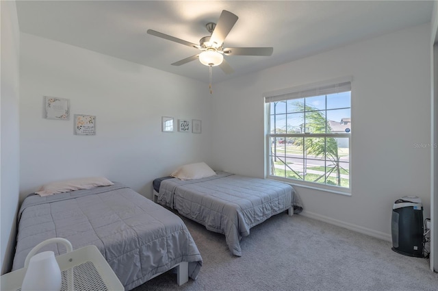 carpeted bedroom with ceiling fan and baseboards