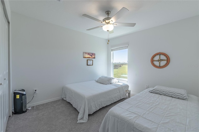 carpeted bedroom featuring a ceiling fan, a closet, and baseboards