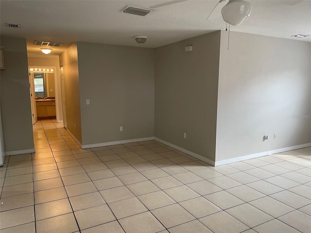 spare room featuring light tile patterned floors, visible vents, and baseboards