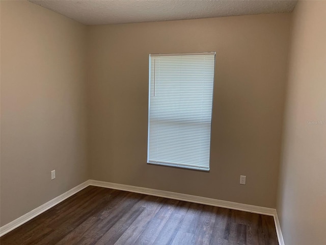 unfurnished room featuring dark wood-type flooring, a textured ceiling, and baseboards