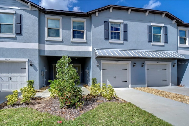 multi unit property with driveway, metal roof, an attached garage, a standing seam roof, and stucco siding