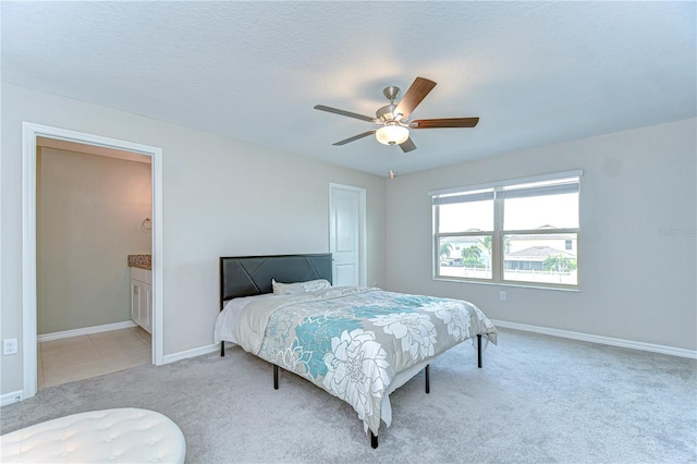 carpeted bedroom featuring ceiling fan, baseboards, a textured ceiling, and ensuite bathroom