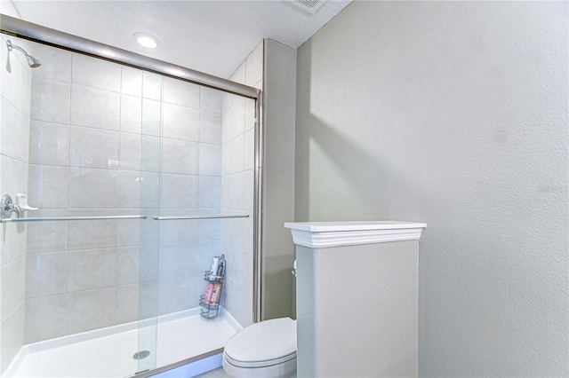 full bath featuring a stall shower, a textured wall, and toilet