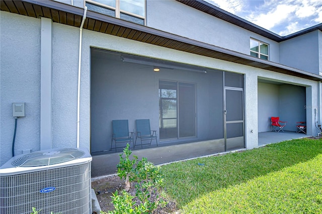 rear view of house featuring central air condition unit, a yard, and stucco siding