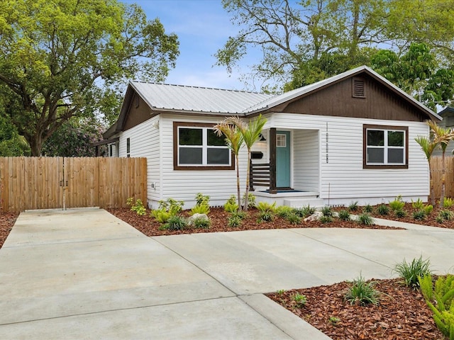 view of front of property featuring metal roof, a porch, and fence