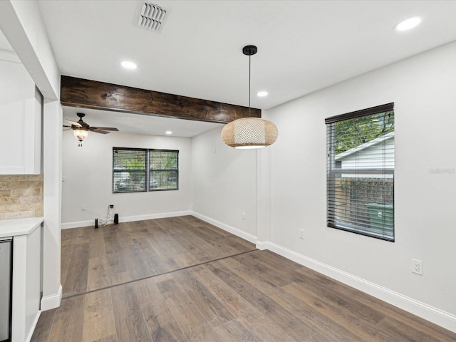 unfurnished dining area featuring wood finished floors, visible vents, baseboards, recessed lighting, and beamed ceiling