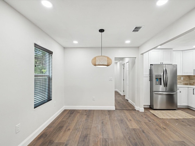 kitchen featuring visible vents, dark wood-style flooring, decorative backsplash, white cabinets, and stainless steel fridge