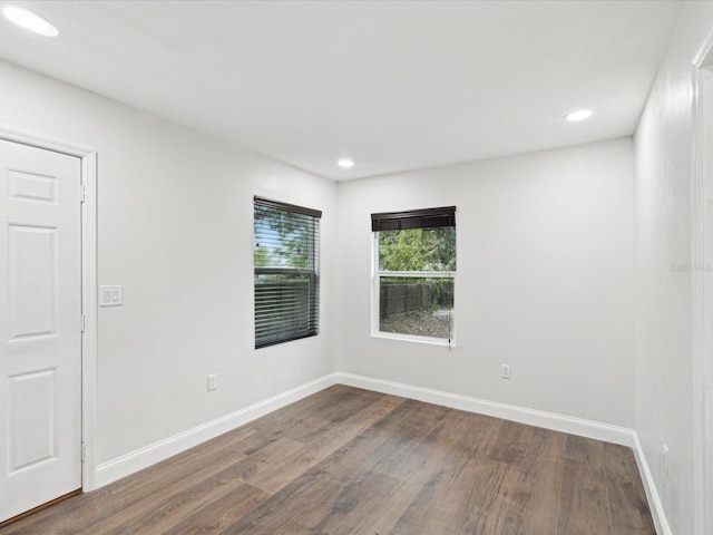 empty room featuring recessed lighting, baseboards, and dark wood finished floors