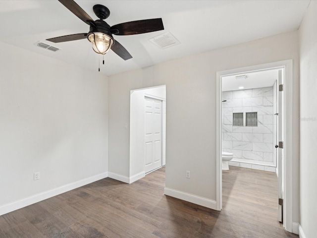 unfurnished bedroom featuring visible vents, baseboards, wood finished floors, and ensuite bathroom