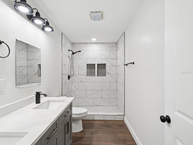 bathroom featuring toilet, wood finished floors, a shower stall, and a sink