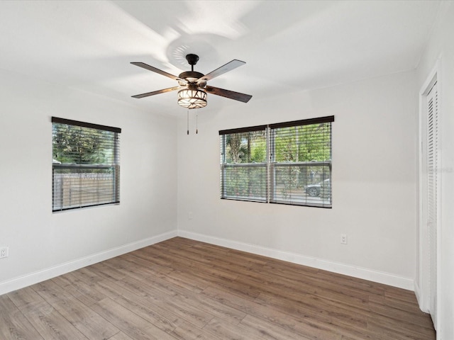 unfurnished room with baseboards, wood finished floors, and a ceiling fan